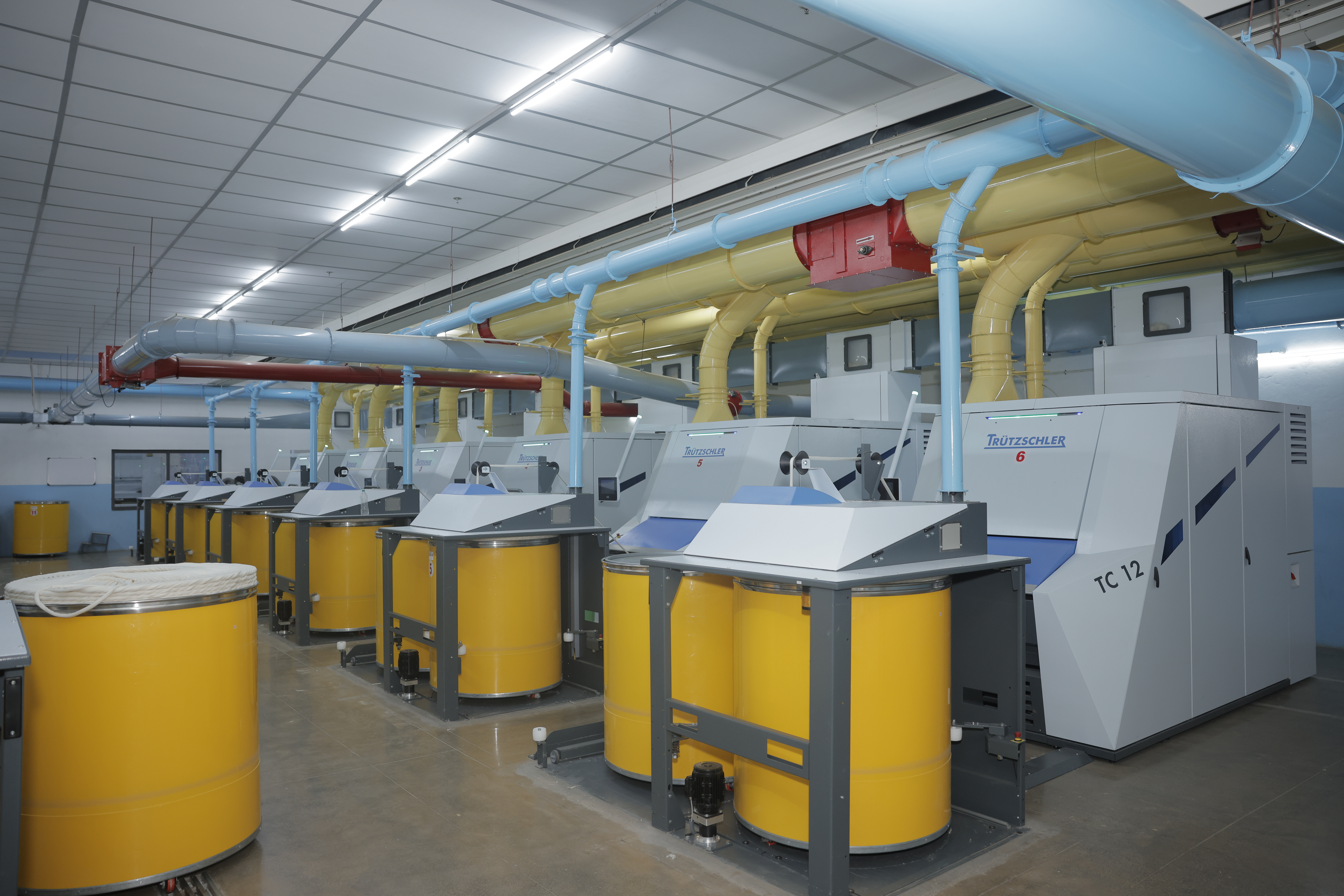 Rows of spinning machines and cotton yarn spools inside Umed's spinning unit